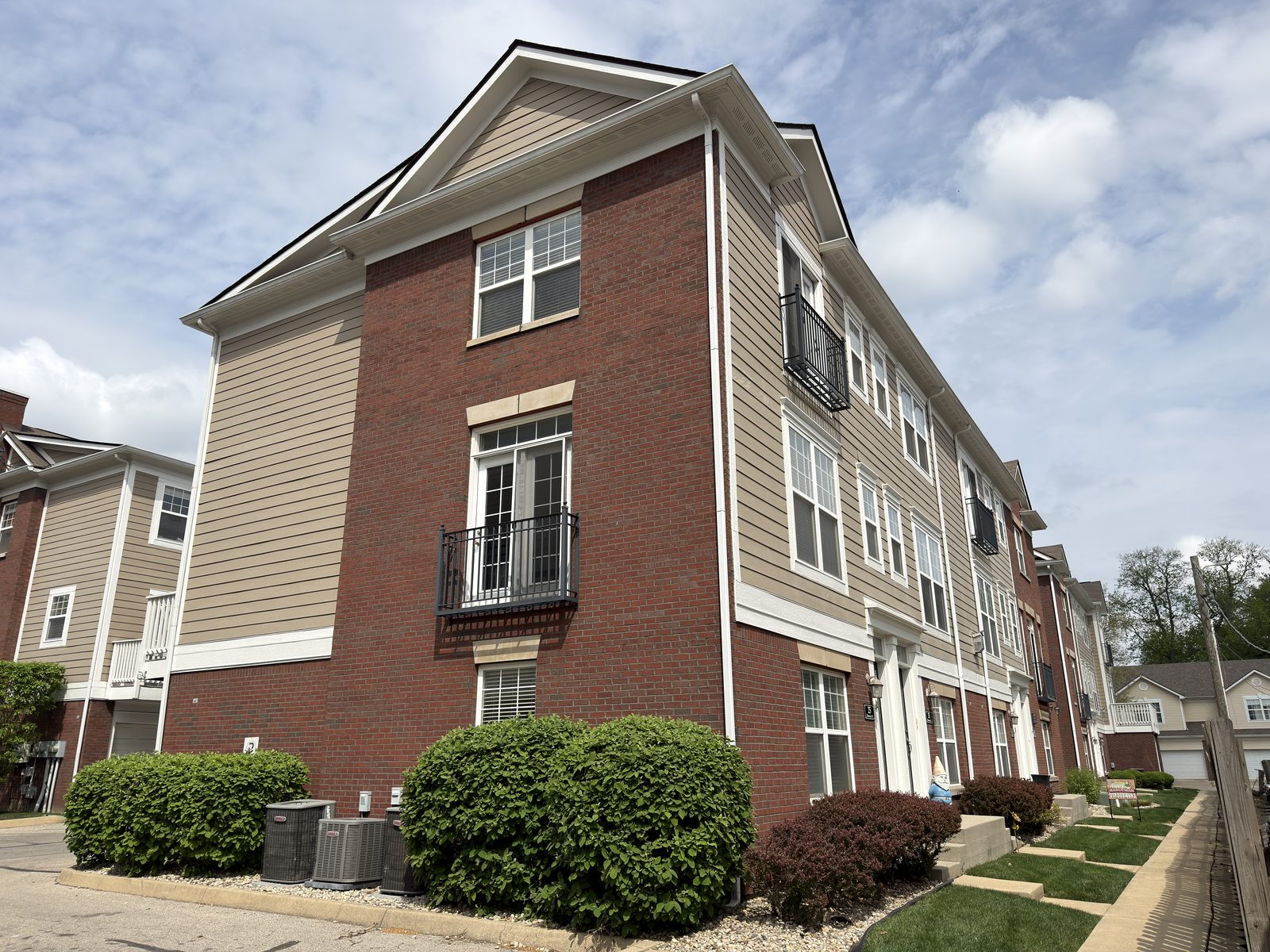 Monon and Main townhome corner detail — balcony, chimney, and trim work close-up after Beacon Painting wood repair and repaint, Carmel IN